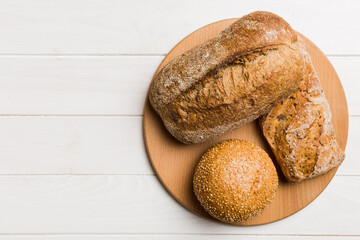 Wall Mural - Freshly baked bread on cutting board against white wooden background. top view bread with copy space