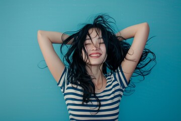 Poster - Portrait of young woman with mid length black hair jumping for joy expressing her mood. Shot in studio on blue background with stripped pattern behind the model.