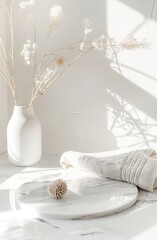 White flowers in a vase on a white table with a towel