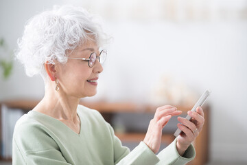 Wall Mural - profile of smiling senior woman holding a smart phone (smartphone)