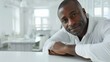 © StudioX180 - Professional black man, leaning on a table in clean white office, approachable look, close-up portrait.