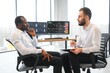 © Serhii - Two men colleagues traders sitting at desk at office monitoring stock market