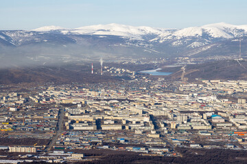 Wall Mural - Top view of the city of Magadan. A large northern city in a valley among the mountains. Many buildings. Snow-capped mountains in the distance. Magadan, Magadan region, Russian Far East.