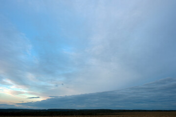 Wall Mural - Sunrise over the field. The sun's rays fall on the plowed fields and on the forest under the mountain.