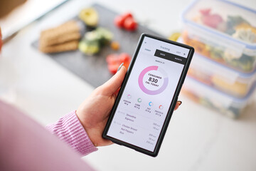 Close Up Of Woman Looking At Calorie Counting App On Mobile Phone At Home