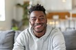 © CogniLens - Portrait of a glad afro-american man in his 20s smiling at the camera over crisp minimalistic living room