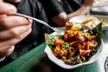 Wall Mural - Close-up of a person enjoying a colorful Asian-style dish with vegetables and rice