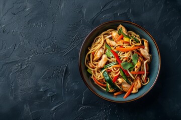 Wall Mural - Bowl with Asian chicken stir fry soba noodles with vegetables on dark black stone background from above, Chinese Thai or Japanese noodles dish with soy sauce. Space for text