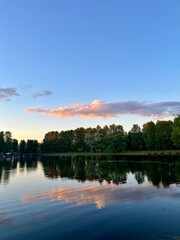 purple clouds reflection on the lake surface, trees silhouettes reflections on the water surface, twilights lake in the park, natural colors, very calm and peaceful