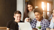 © Prostock-studio - A diverse group of students are gathered around a laptop, attentively looking at the screen. They appear to be engaged in a discussion or viewing content together.