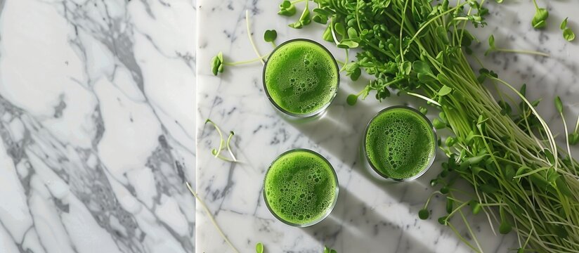A marble table showcasing glasses of wheatgrass juice with green sprouts, offering ample room for text in the image.