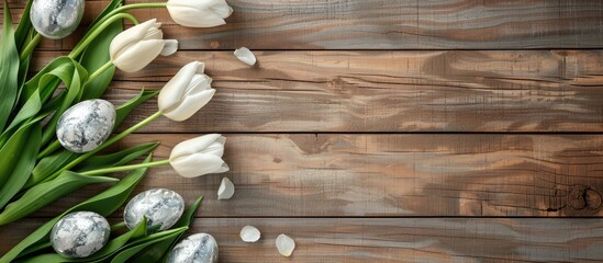 Canvas Print - Colorful silver Easter eggs and tulips set on a brown wooden backdrop in a top view composition with a copy space image, creating a cheerful Easter-themed background.