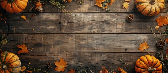 Autumn-themed rustic wooden background adorned with mature pumpkins, dried herbs, and yellow maple leaves, suitable for showcasing images or text. Top-down view portraying the essence of fall harvest