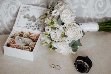 Wall Mural - A bouquet of white flowers sits on a table next to a white box and a watch. The flowers are arranged in a vase and the box contains a pair of earrings
