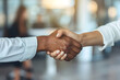 © mediahain.de - A high-resolution photo of two businesswomen shaking hands in an office setting, with a successful business negotiation in the background, creating a sense of partnership and achievement