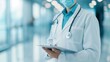 © Stone Story - Healthcare professional wearing a mask and lab coat, using a digital tablet in a modern medical facility with a bright, blurred background.