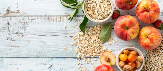 A table with a selection of nutritious breakfast foods like oat flakes, ripe apples, and peaches on a white wooden surface offers a pleasing background for health-conscious viewers. Includes copy