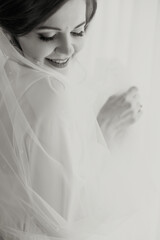 Wall Mural - A bride is posing for a picture with her veil pulled back. She is smiling and looking at the camera