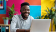© Steven - A happy man working on his laptop in a vibrant and colorful office space embodying creativity, productivity, and a positive work environment