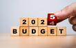 © Dilok - Hand flipping wooden block cube for change 2024 to 2025 Budget for money planning and allocation concept.