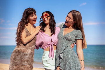 Cheerful multiethnic friends with sunglasses happy on vacation on the beach.