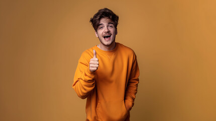 Excited Young Man in Bright Orange Hoodie Giving Thumbs Up with Enthusiastic Expression