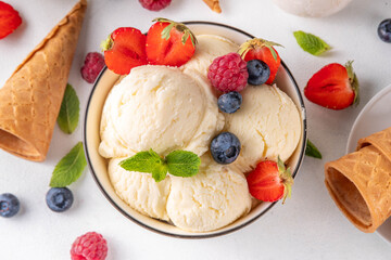 Wall Mural - White ice cream bowl with vanilla gelato and fresh berries. Big portion of classic vanilla taste ice cream, with strawberry, raspberry, blueberry, blackberry, and waffle ice cream cones