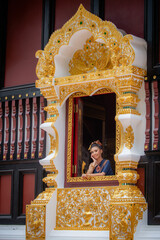 Wall Mural - Woman wearing Thai dress visits beautiful temple in Thailand.