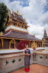 Wall Mural - Woman wearing Thai dress visits beautiful temple in Thailand.