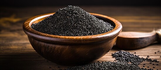 Poster - Black sesame seeds spice arranged in a pile on a black wooden surface with an available area for additional content, like a copy space image.