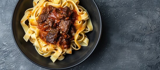 Poster - Top view of a black bowl filled with fettuccine pasta and beef ragout sauce on a grey backdrop, ideal for adding text or images (copy space image).