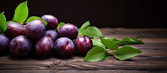 Fototapete - Plums freshly picked and arranged on wooden surface with green foliage, providing ample space for additional images.