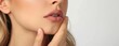 © kazitafahnizeer - Semi-close-up of a woman with a sore throat touching her neck, medical clinic background, realistic skin detail, ample copy space