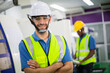 © winnievinzence - Portrait of smiling male engineer foreman in safety hardhat standing in the factory production. man operating machine at industrial plant. men at work concept.
