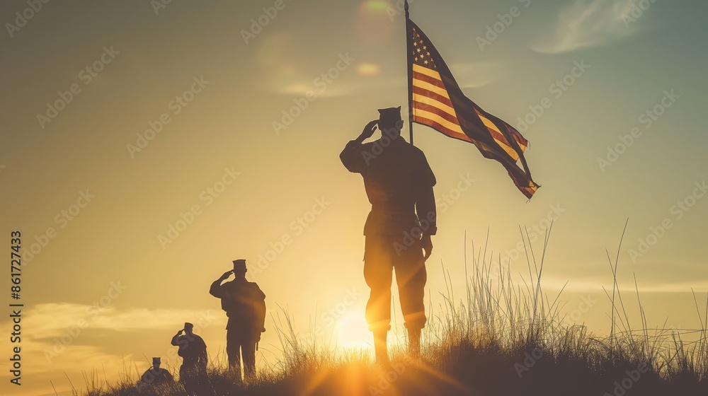 Silhouetted soldiers performing a salute during a vibrant sunset with ...