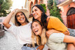 © Davide Angelini - Three multiethnic girls having fun walking in city street - Happy young women laughing together enjoying summertime vacation