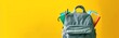 © Gromik - A yellow background with a backpack filled with school supplies, with copy space