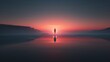 © May Chanikran - Silhouette of a person standing on a reflective surface with a stunning sunrise or sunset background, showcasing serene beauty and tranquility.