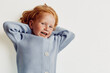 © SHOTPRIME STUDIO - Happy little girl leaning against wall in blue sweater smiling, childhood joy and innocence portrait