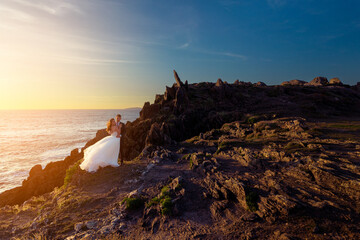 Wall Mural - Bride and groom near a cliff at sunset