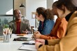 © Mediaphotos - Diverse group of business people sitting at meeting table in office with senior African American man instructing employees copy space