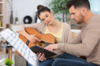 © auremar - young happy and loving couple study to play acoustic guitar