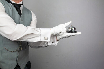 Butler or Hotel Concierge in Waistcoat and White Gloves Holding Serving Bell. Ring for Service Concept.