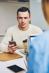 Canvas Print - Portrait of serious candidate for vacancy looking at camera checking mail with online letter sitting in office during interview,male worker looking at camera chatting via smartphone on coffee break