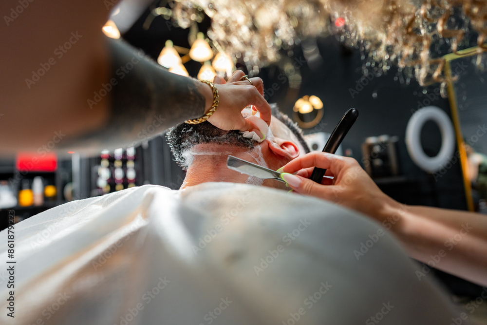 Barber carefully shaves under the neck with a straight razor, focusing ...