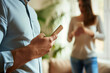 © Ala - Husband Uses Smartphone While Wife Stands in Background