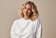 © CS - Smiling blonde woman wearing white sweatshirt against brown backdrop