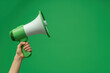 © Alexandra - Hand holding a megaphone against a green background, perfect for conveying messages with attention-grabbing communication. Ideal for activism, marketing, or raising awareness