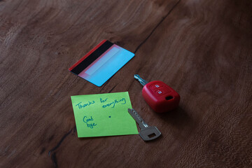 A goodbye note on a wooden table next to a credit card, two keys and a ring implying a tragic breakup 