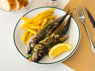 Sticker - Grilled mackerel fish with french fries and lemon on a white plate